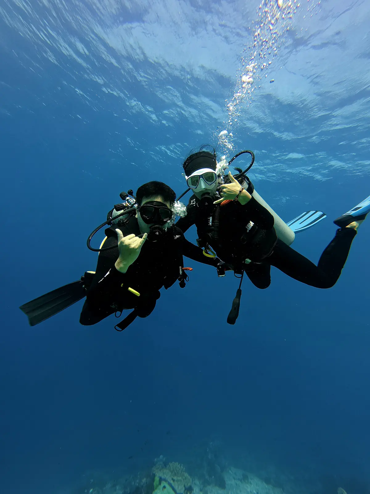Two Mai Explore divers giving the shaka sign underwater
